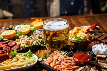 Front view of beer snacks with lemon wedges on a stand with a glass of beer Front view of beer snacks with lemon wedges on a stand with a glass of beer