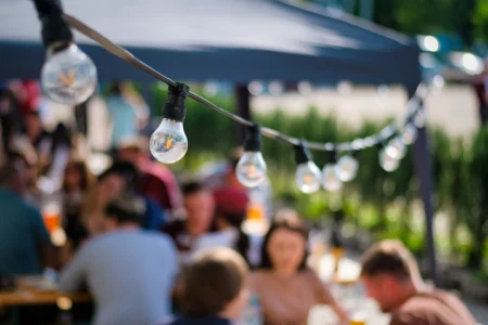 Hanged lamps at outdoor restaurant with multiple visitors on the background Hanged lamps at outdoor restaurant with multiple visitors on the background