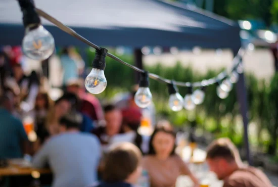 Hanged lamps at outdoor restaurant with multiple visitors on the background Hanged lamps at outdoor restaurant with multiple visitors on the background